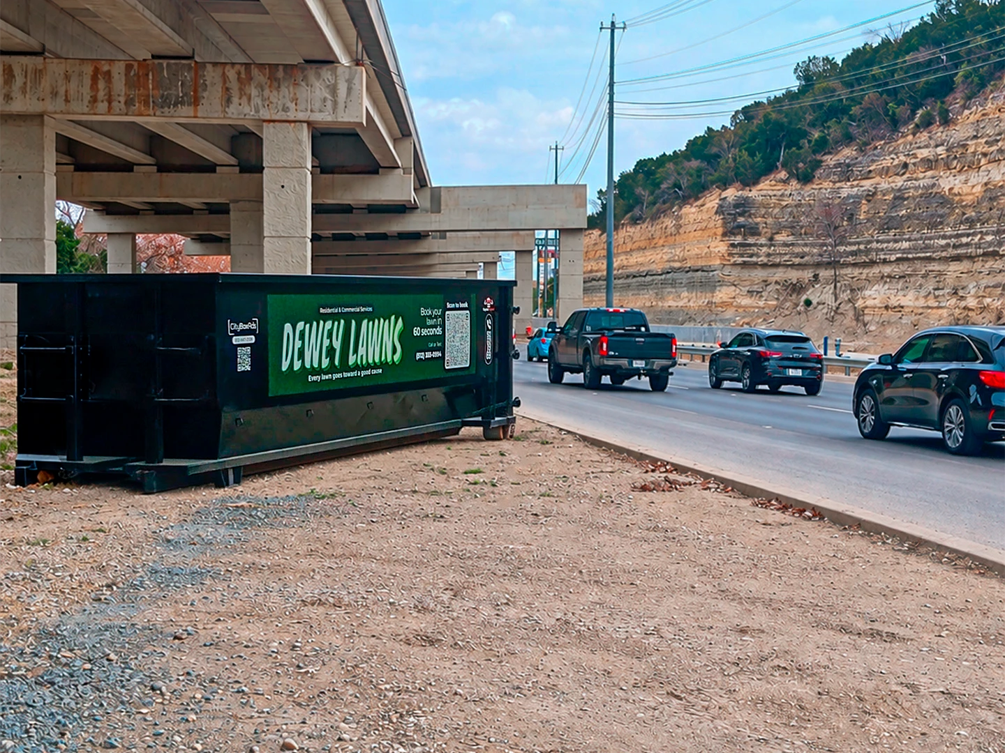 Dewey Lawns advertising container beneath a highway overpass